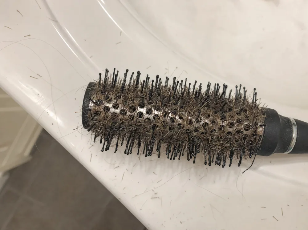 Haarbürste voller kurzer, abgebrochener Haare am Waschbecken