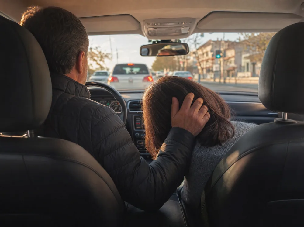 Hand eines Mannes streicht im Auto über das Haar der Beifahrerin